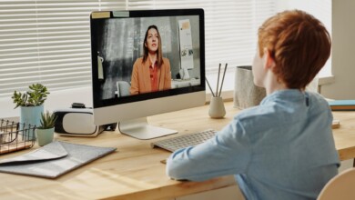 photo of child sitting by the table while looking at the imac