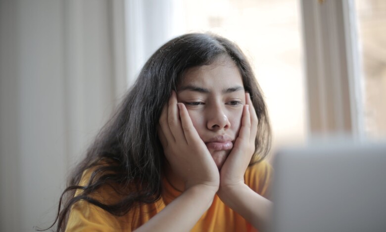 melancholic woman watching video on laptop at home