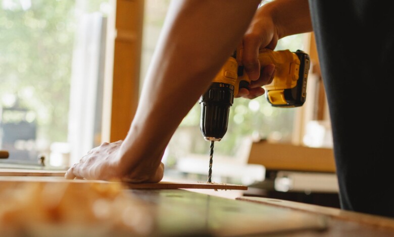 man drilling wooden plank on desk