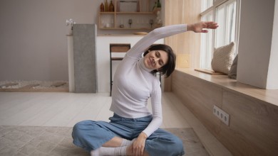smiling woman practicing yoga with closed eyes at home