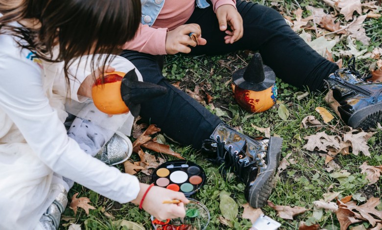crop children painting pumpkins in autumn park