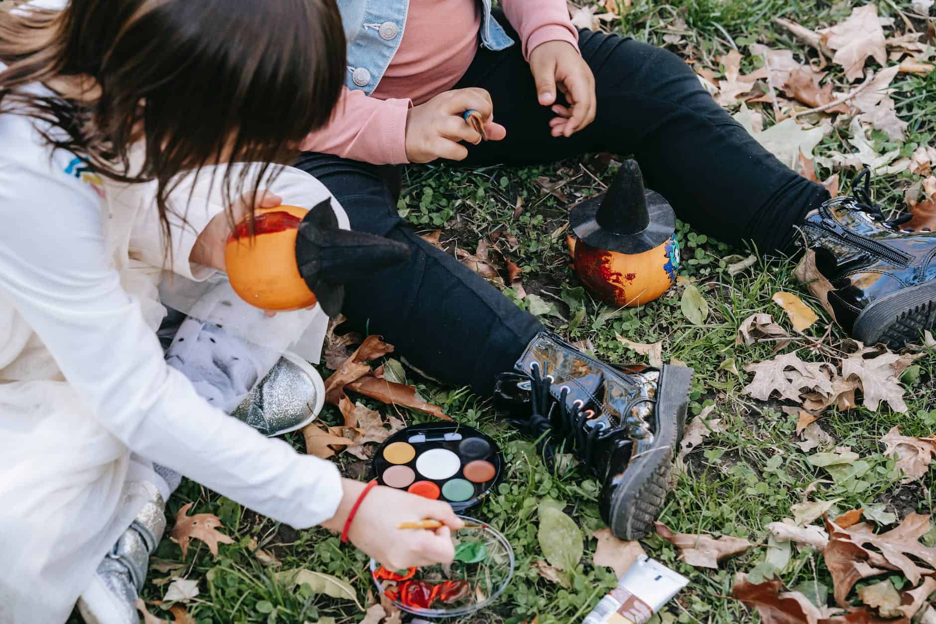 crop children painting pumpkins in autumn park