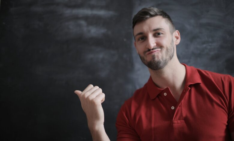 man in red polo shirt standing beside chalk board