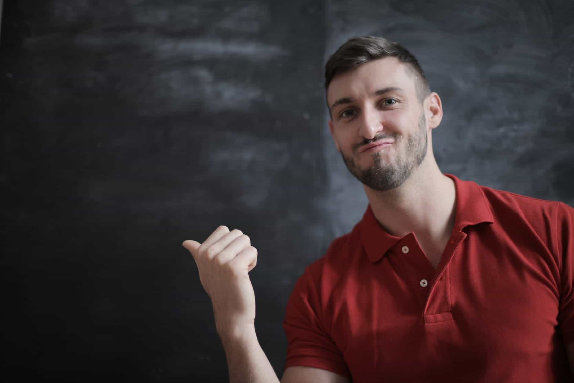 man in red polo shirt standing beside chalk board