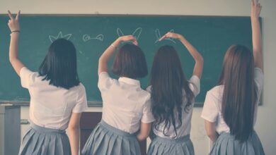 photo of four girls wearing school uniform doing hand signs