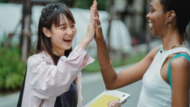 joyful diverse students giving high five in park