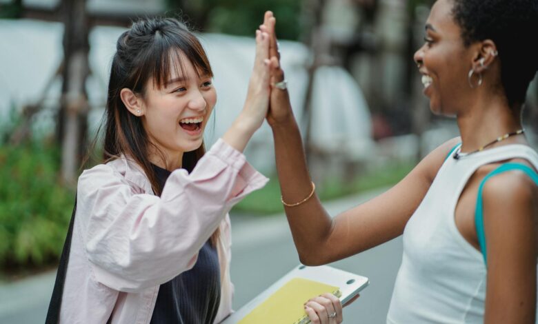 joyful diverse students giving high five in park