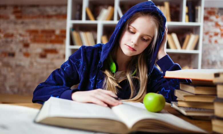 woman wearing blue jacket sitting on chair near table reading books