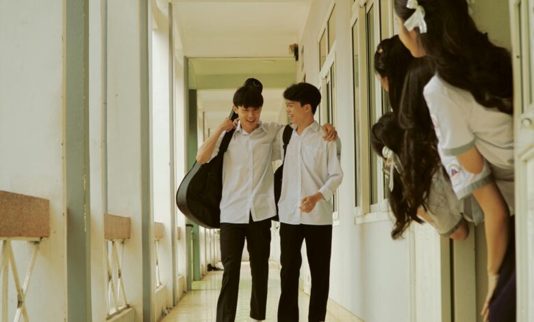 schoolboys walking down the corridor watched by a group of schoolgirls hiding behind the classroom door