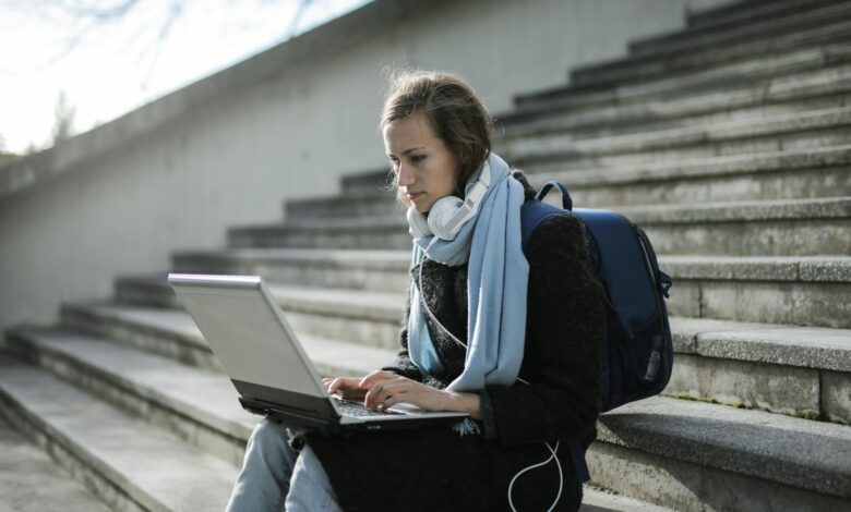 woman sitting on concrete stairs using laptop