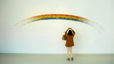 woman wearing brown top and beige leggings taking picture rainbow painted wall