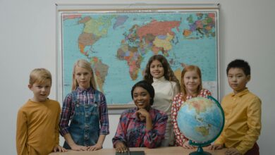 teacher and a group of children standing beside table with globe