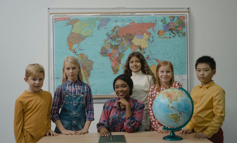 teacher and a group of children standing beside table with globe