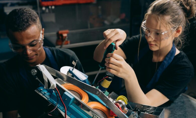 woman in black shirt wearing protective goggles holding black and green screw driver