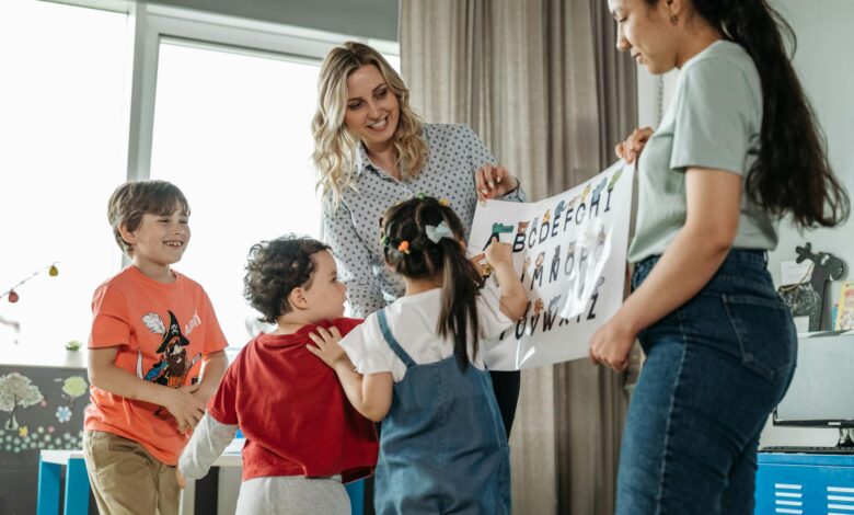 teachers holding a poster of the alphabets