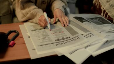 close up on woman s hand while searching for job postings in newspaper
