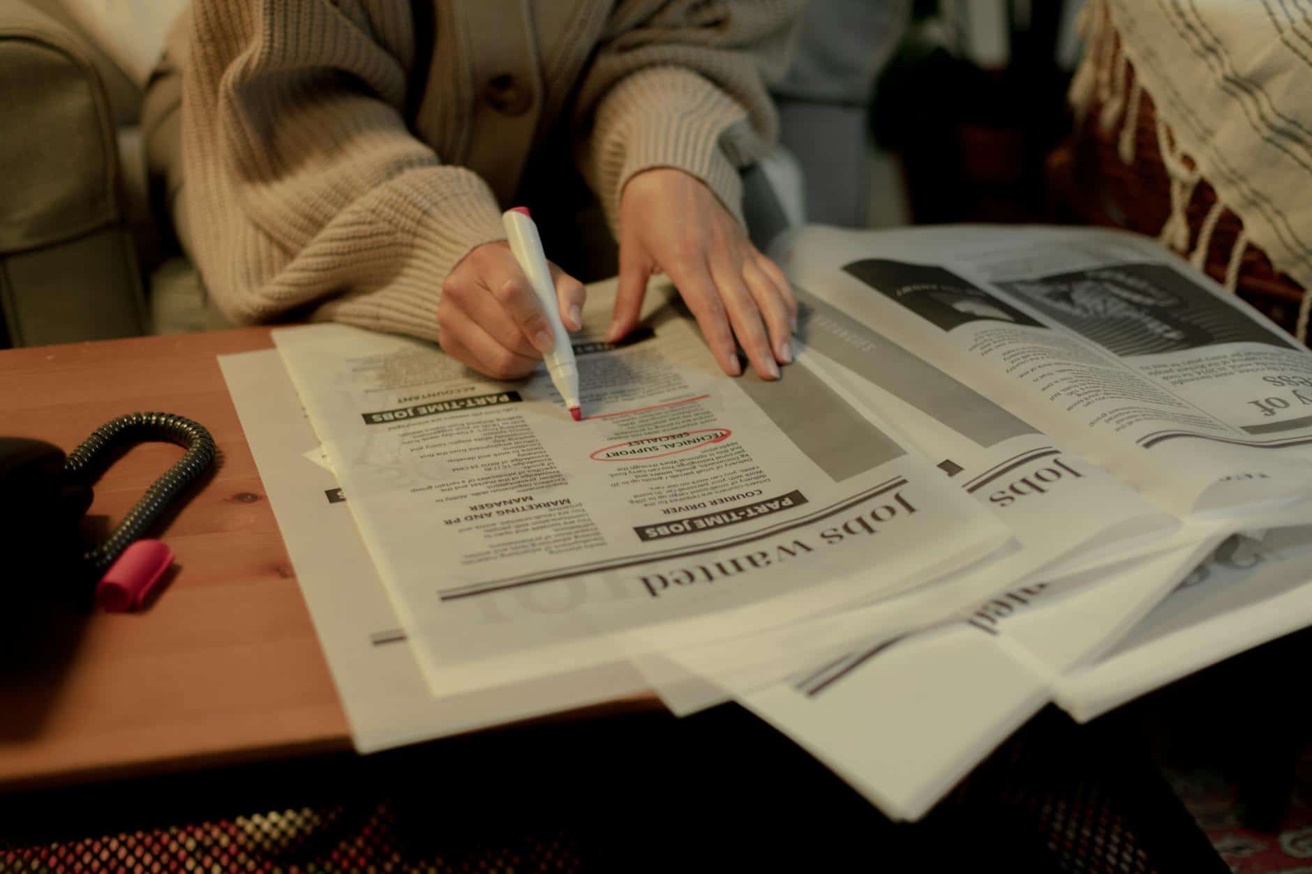 close up on woman s hand while searching for job postings in newspaper