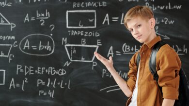 boy in brown jacket standing in front of chalk board