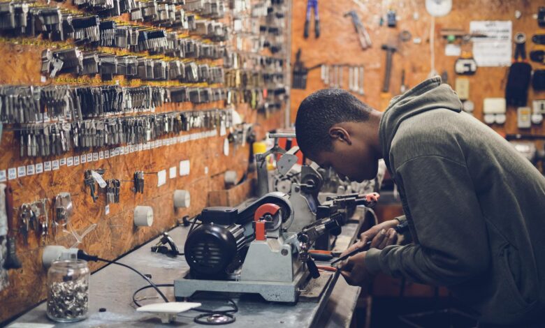 man in grey hoodie jacket holding black metal near white socket power supply