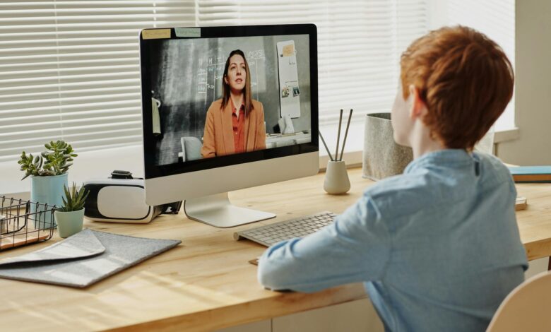 photo of child sitting by the table while looking at the imac