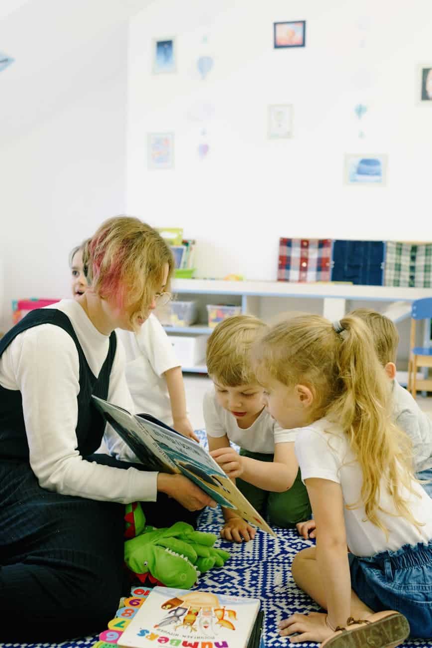 children in the school reading a book with a teacher
