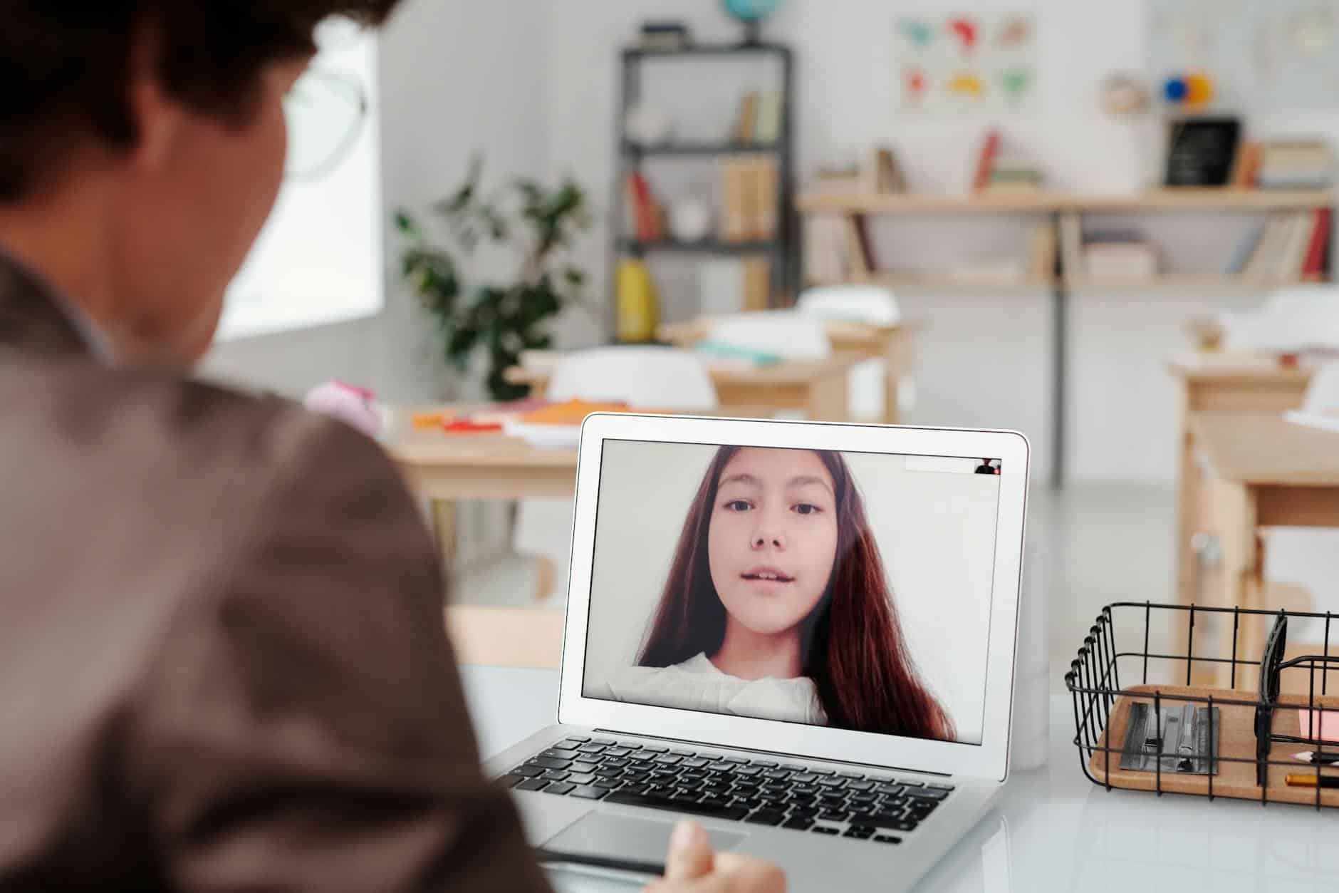 a teacher teaching a girl using laptop