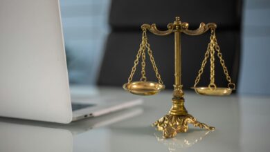 a golden balance scale beside a laptop