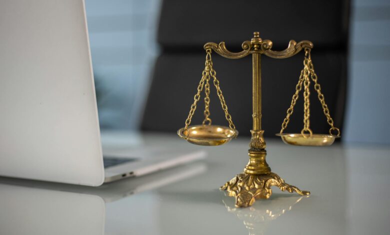 a golden balance scale beside a laptop