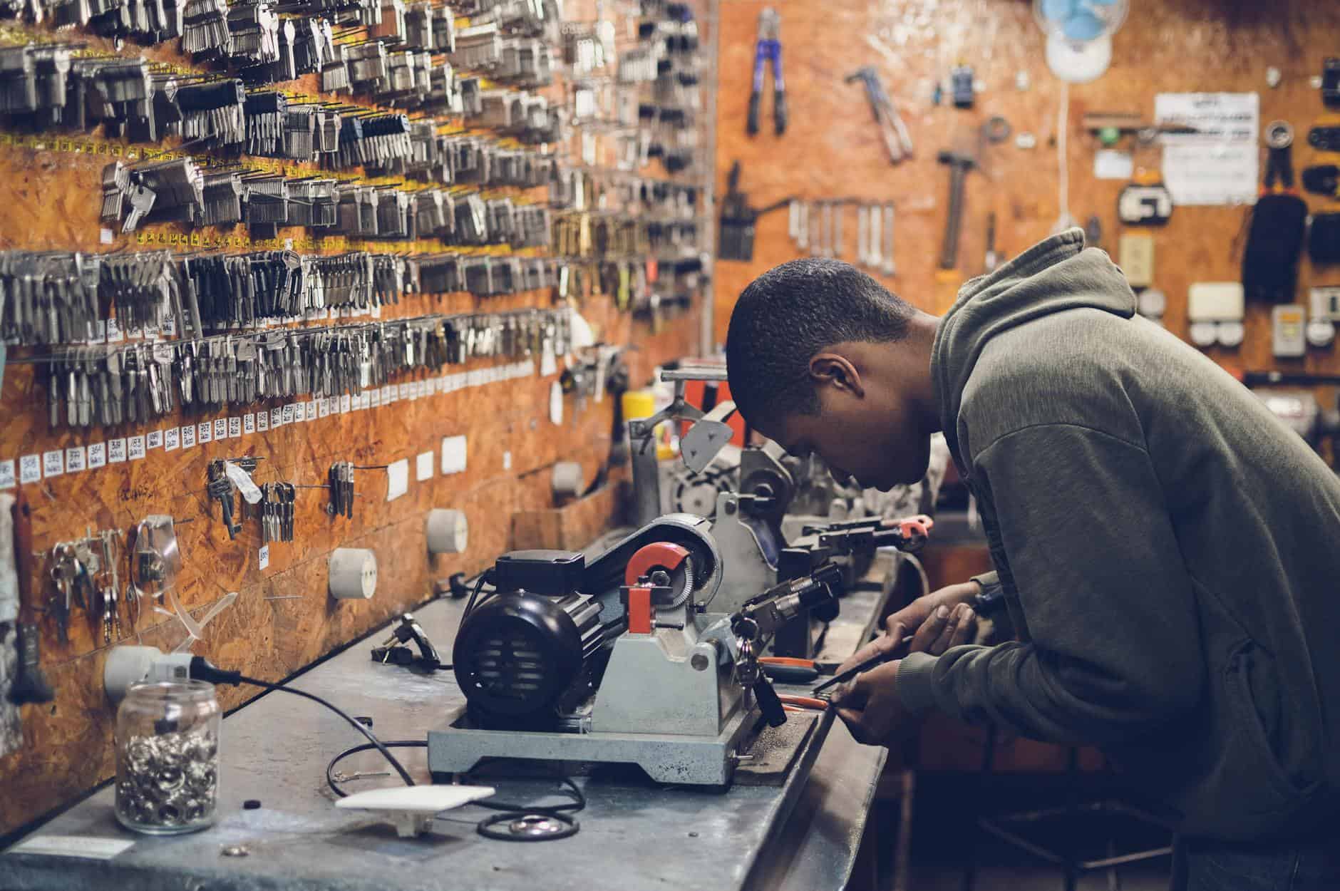 man in grey hoodie jacket holding black metal near white socket power supply
