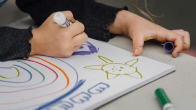 crop child drawing rainbow and sun