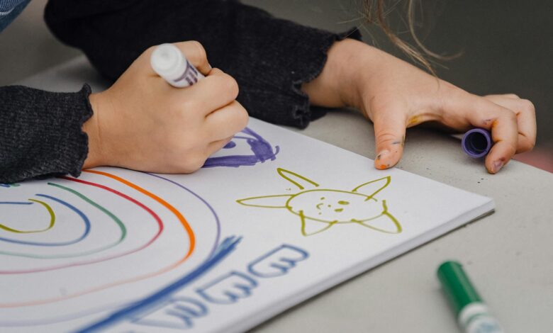 crop child drawing rainbow and sun