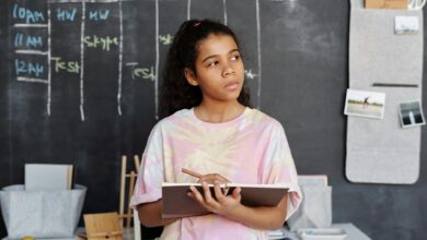woman in pink and yellow crew neck t shirt holding brown notebook