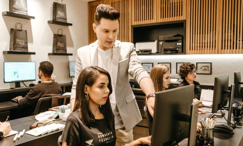 man teaching woman in front of monitor
