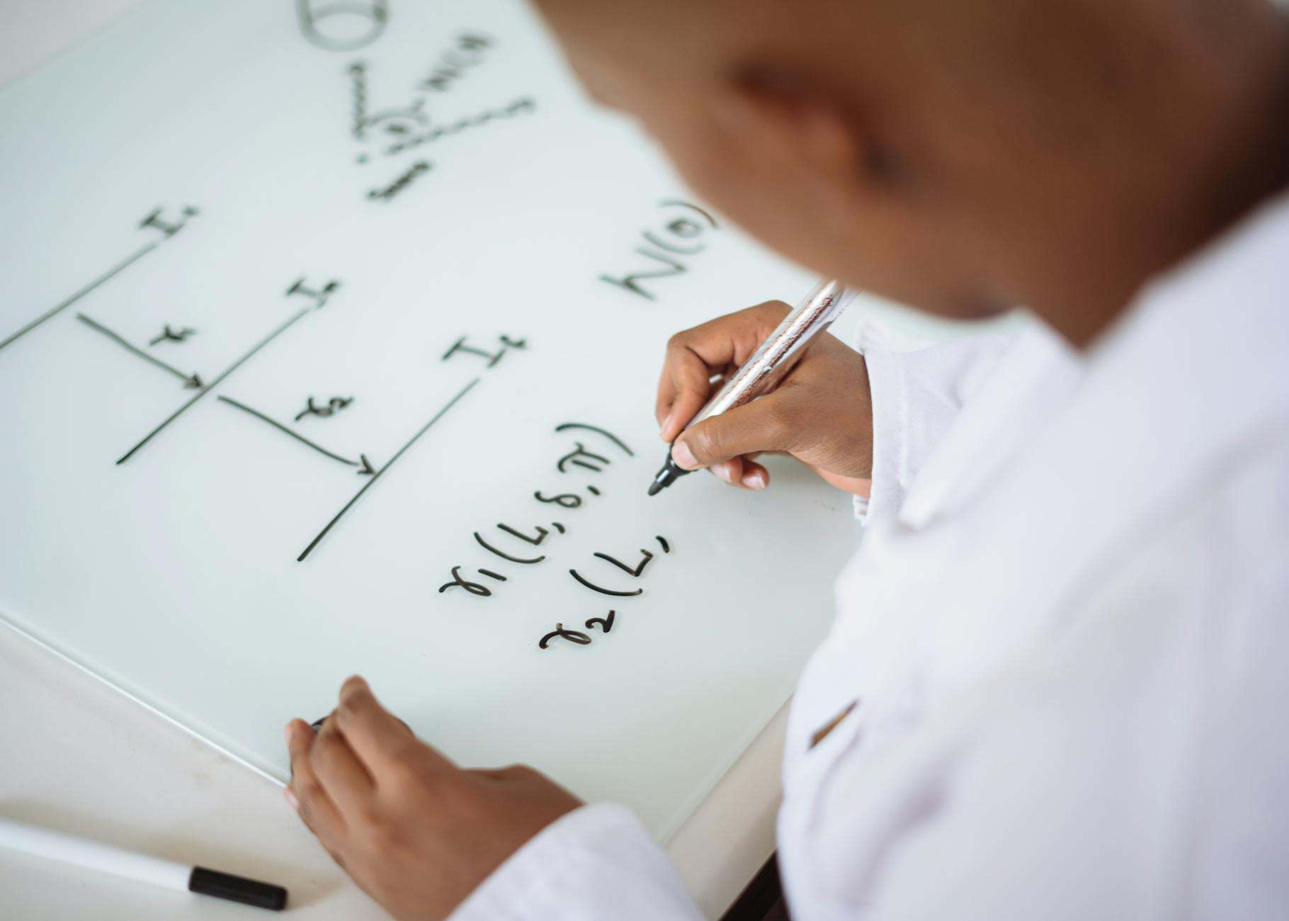 photo of person deriving formula on white board
