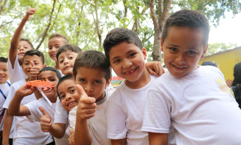group of children wearing white crew neck t shirts smiling at camera