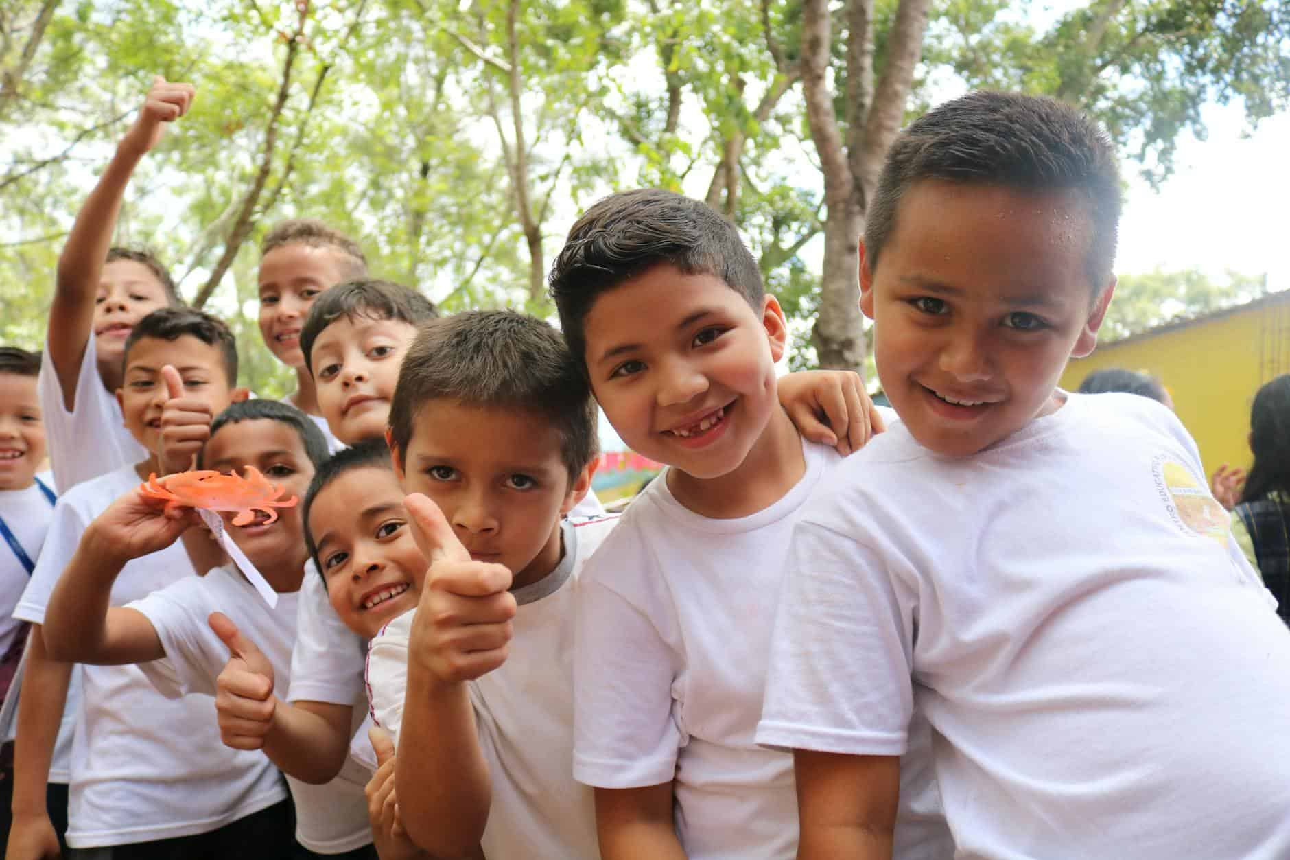 group of children wearing white crew neck t shirts smiling at camera