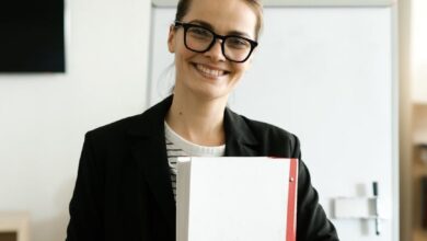 a happy woman in a black blazer and eyeglasses