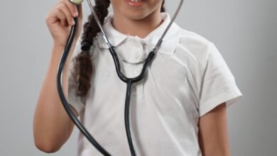 girl in white polo shirt wearing a stethoscope playing doctor