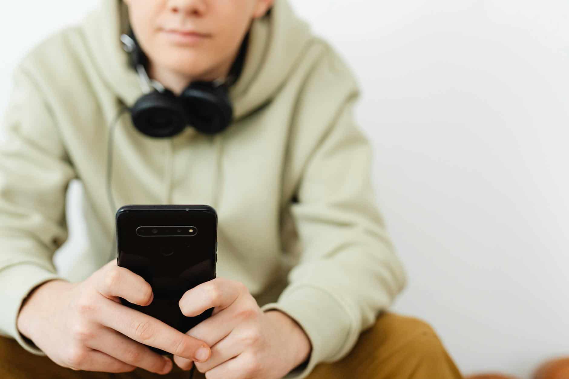 man in wearing hoodie using a smartphone