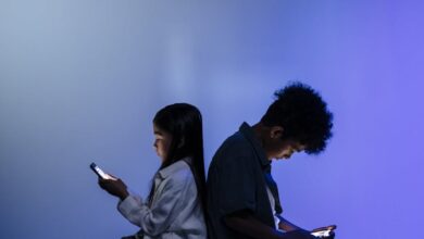 kids sitting back to back using smartphone