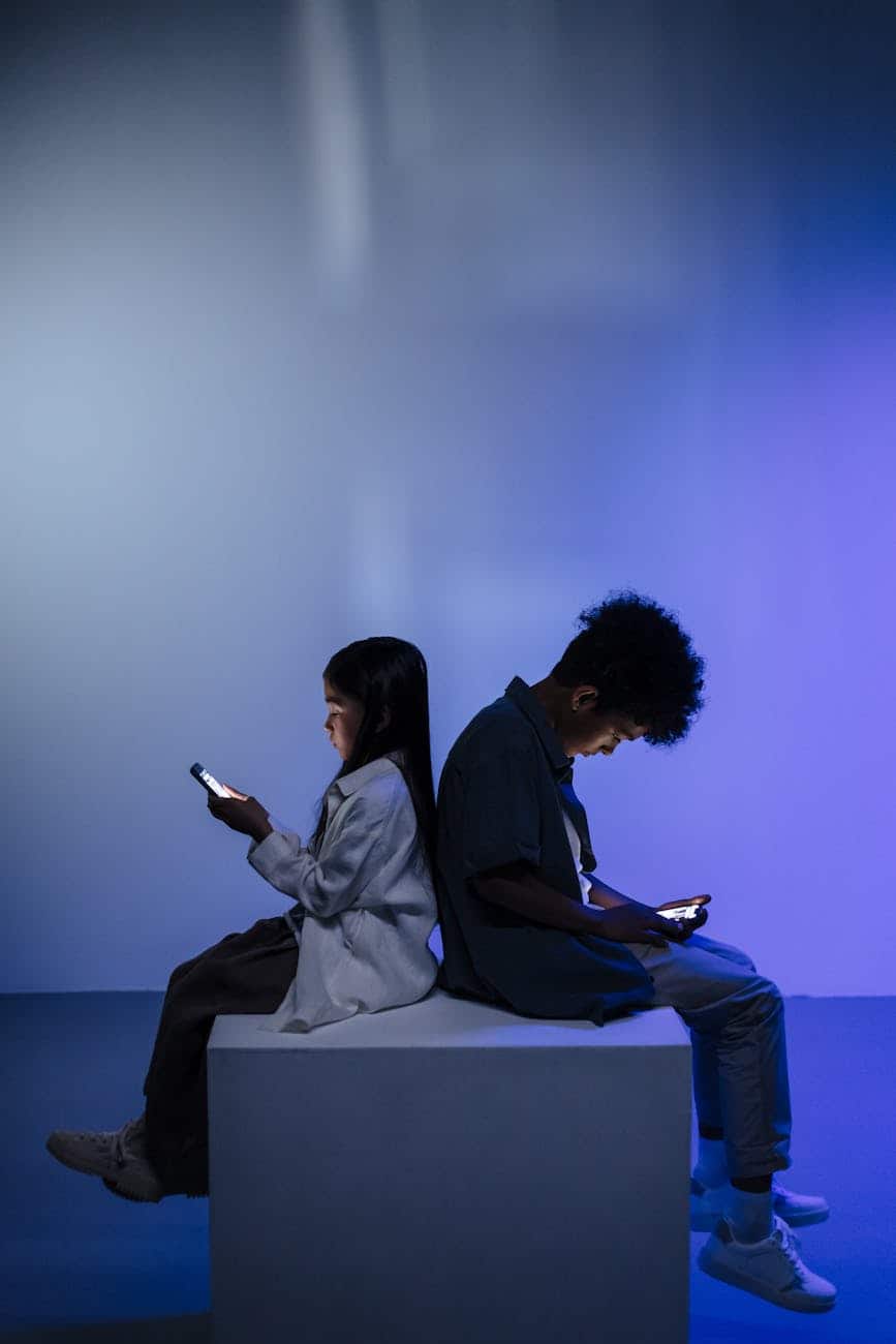 kids sitting back to back using smartphone