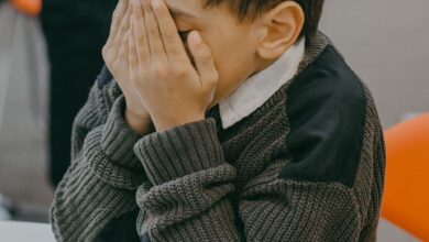 a boy covering his face with his hands
