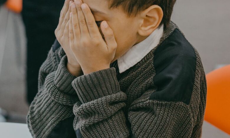 a boy covering his face with his hands