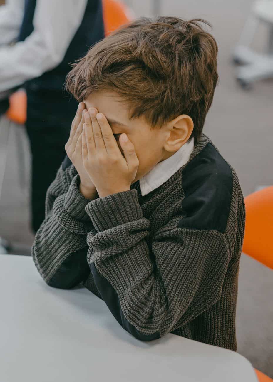 a boy covering his face with his hands