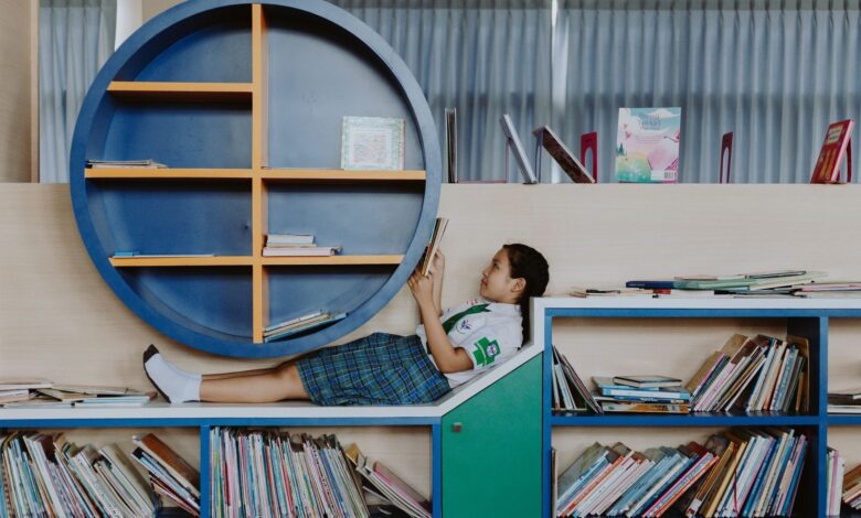 girl in school uniform lying on book shelf and reading