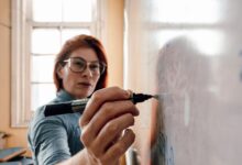 female teacher writing on whiteboard in classroom