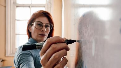 female teacher writing on whiteboard in classroom
