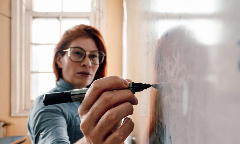female teacher writing on whiteboard in classroom