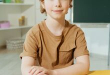 cute boy in brown shirt sitting by the yellow table