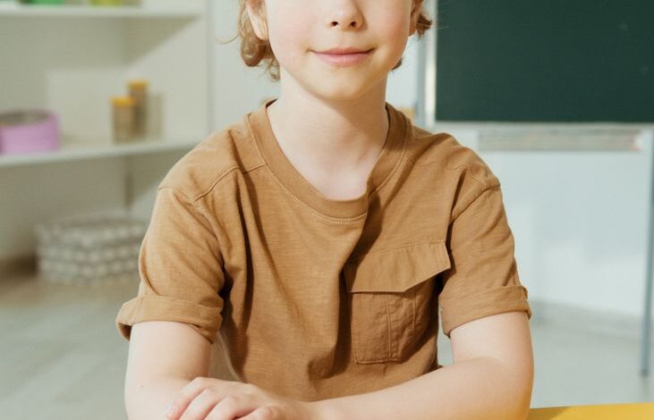 cute boy in brown shirt sitting by the yellow table